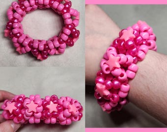 Könnte beinhalten: Eine Sammlung von rosa und magenta Perlenarmbändern. Eines ist ein voller Kreis, andere werden am Handgelenk getragen. Einige Armbänder haben rosa sternförmige Akzente. Die Perlen sind klein und rund.