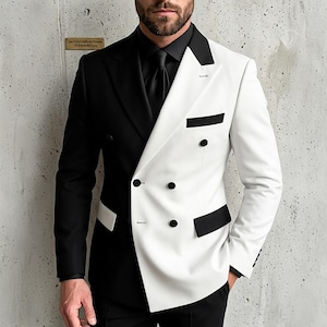 Op de afbeelding: Een double-breasted blazer met een tweekleurig ontwerp, bestaande uit een effen zwarte rechterkant en een effen witte linkerkant. Het kledingstuk is voorzien van een zwarte revers, zwarte knopen, een zwarte borstzak en twee zwarte klepzakken.