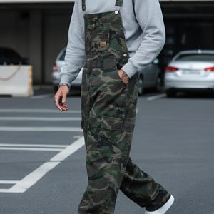 Men's slim-fit camouflage denim bib overalls with adjustable shoulder straps and multiple pockets in an urban streetwear design