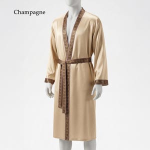 May include: Champagne-colored satin robe with a decorative brown trim along the edges, collar, and belt. The robe is knee-length and has long sleeves. The word "Champagne" is printed in the upper left corner.