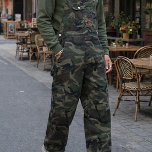Men's slim-fit camouflage denim bib overalls with adjustable shoulder straps and multiple pockets in an urban streetwear design