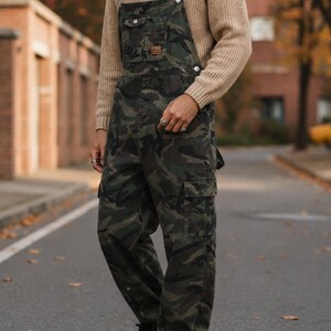 Men's slim-fit camouflage denim bib overalls with adjustable shoulder straps and multiple pockets in an urban streetwear design