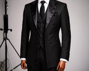 May include: A formal black double-breasted suit with a matching vest, black tie, and pocket square. The suit features a satin lapel and is displayed on a mannequin. The white dress shirt's cuffs are visible.