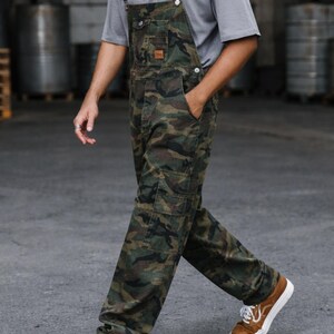 Men's slim-fit camouflage denim bib overalls with adjustable shoulder straps and multiple pockets in an urban streetwear design