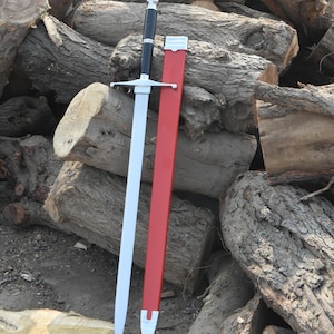 May include: A long, silver sword with a black handle and crossguard, resting against a red sheath. The sword is displayed against a backdrop of stacked logs, showcasing a medieval or fantasy theme.