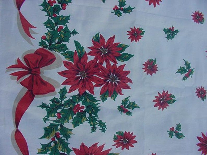 May include: White tablecloth with a red and green Christmas pattern. The pattern features poinsettia flowers, holly leaves, and red bows.