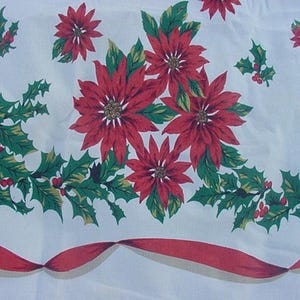 May include: White tablecloth with a red and green Christmas pattern. The pattern features poinsettia flowers, holly leaves, and red berries. A red ribbon with a white border runs along the bottom edge of the tablecloth.
