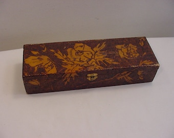 May include: A wooden box with a floral design. The box is painted brown with a yellow floral pattern. The box has a metal clasp.