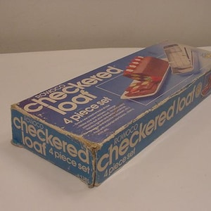 May include: A blue and white box with the text "Rowoco Checkered Loaf 4 piece set" on it. The box contains a set of four checkered loaf pans.