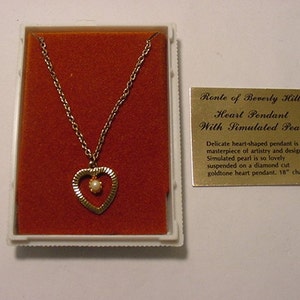 Puede incluir: Collar de corazón de oro con una perla simulada en el centro. El collar mide 45,7 cm de largo y viene en una caja de terciopelo rojo. La caja tiene una etiqueta dorada que dice "Ronte of Beverly Hills Heart Pendant With Simulated Pearl". El delicado colgante en forma de corazón es una obra maestra de la artesanía y el diseño. La perla simulada es tan hermosa que está suspendida en un colgante de corazón de oro de corte de diamante. Cadena de 45,7 cm.