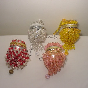 Puede incluir: Cuatro adornos de cuentas en diferentes colores: rojo y transparente, rosa y transparente, amarillo y transparente, y plateado y transparente. Los adornos son todos redondos y tienen una franja de cuentas.