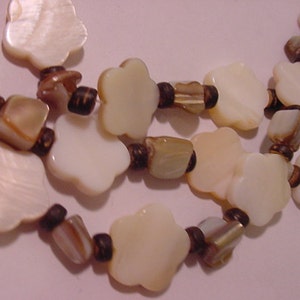 May include: A double strand necklace made of white shell flower-shaped beads and brown wooden beads.
