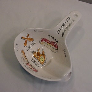 Puede incluir: Separador de salsa blanco de cerámica con asa. El separador está dividido en secciones etiquetadas como "Fat", "Chicken", "Turkey", "Steak", "Gravy" y "Lean".