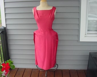 May include: A sleeveless pink dress with a fitted bodice and a full skirt. The dress is made of a smooth, silky fabric.