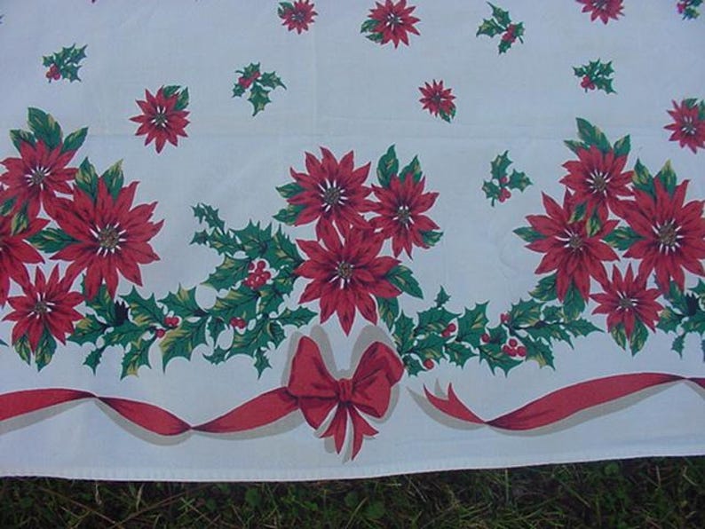 May include: White tablecloth with a red and green Christmas pattern. The pattern features poinsettia flowers, holly leaves, and red bows.