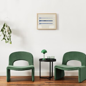 Puede incluir: Dos sillas de terciopelo verde con una mesa auxiliar negra entre ellas. La mesa tiene una l&aacute;mpara verde con una pantalla blanca y dos candelabros de vidrio transparente. Las sillas tienen un dise&ntilde;o &uacute;nico con un respaldo curvo y un asiento ancho.