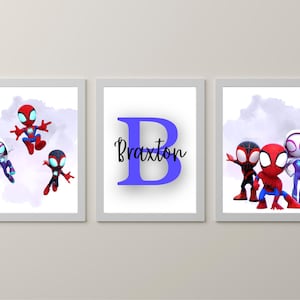 May include: Three framed art prints featuring Spider-Man characters. One print has the name "Braxton" with a large blue letter "B". The other two prints show Spider-Man characters in action poses, with a purple watercolour background.