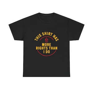 May include: Black t-shirt with the text "THIS SHIRT HAS MORE RIGHTS THAN I DO" in yellow and red. The text is arranged in a circular design with an arrow pointing upwards.
