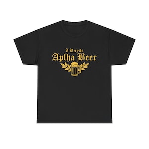 Puede incluir: Camiseta negra con texto dorado y un diseño de jarra de cerveza. El texto dice "I Recycle Aplha Beer" en una fuente adornada, con una jarra de cerveza y hojas debajo. Prenda de vestir informal.