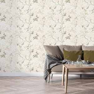 May include: A living room scene featuring a beige sofa with olive green and beige pillows, a wooden coffee table, and a floral wallpaper background. The wallpaper has a cream base with delicate green and brown botanical patterns.