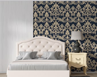 May include: A cream-colored upholstered bed with a tufted headboard and gray pillows and bedding. A nightstand with a lamp sits beside the bed. The wall behind the bed features a navy blue and gold damask pattern.