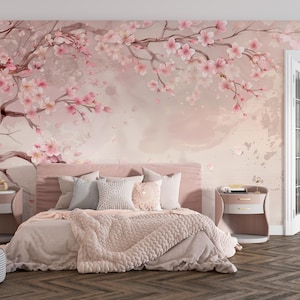 Puede incluir: Una habitación con un mural floral rosa y blanco, con una cama, mesitas de noche y un puf estampado. La cama tiene un cabecero rosa, ropa de cama blanca y una manta de punto rosa. La habitación tiene una estética suave y romántica.