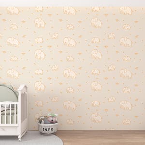 May include: A nursery scene featuring a white crib with a green headboard, a plush elephant toy, and a basket labeled "TOYS." The walls are adorned with a repeating pattern of beige elephants on a cream background, creating a playful and inviting atmosphere.