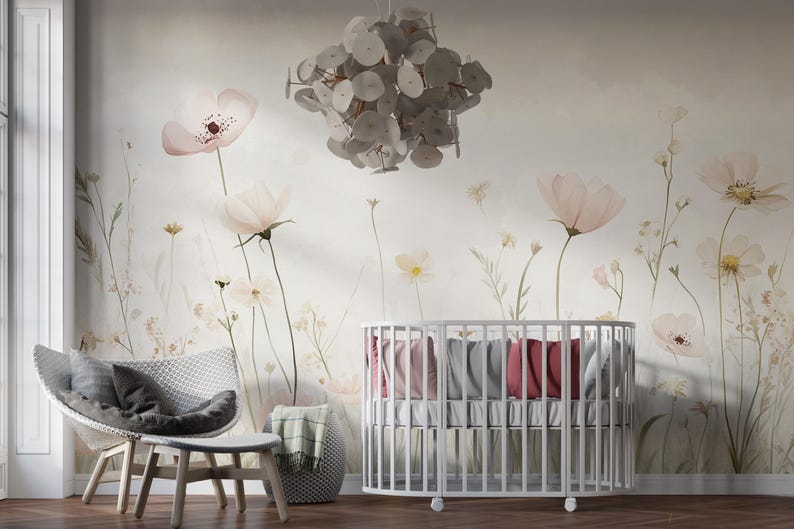 Pu&ograve; includere: Una scena di asilo nido con una culla bianca, una sedia moderna e carta da parati floreale. La carta da parati mostra grandi e delicati fiori rosa e bianchi. Un lampadario decorativo pende dal soffitto.