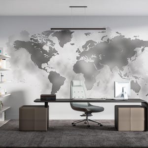 May include: Modern office space featuring a large black desk with a gray leather chair and two matching ottomans. A world map mural adorns the wall, and a computer monitor sits on the desk. Shelving units are on the left.