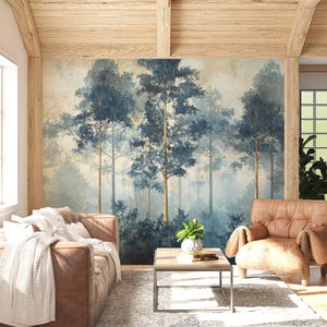 May include: A living room interior design with a large wall mural featuring a blue and white watercolour painting of a forest. The mural is behind a brown leather sofa and a brown leather armchair. A small coffee table with a plant and books sits in front of the sofa.