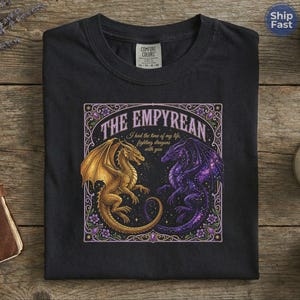 May include: Black t-shirt featuring a detailed graphic of two dragons facing each other. One dragon is gold, the other is purple with a starry wing design. The text "THE EMPYREAN" and "I had the time of my life, fighting dragons with you" are also displayed.