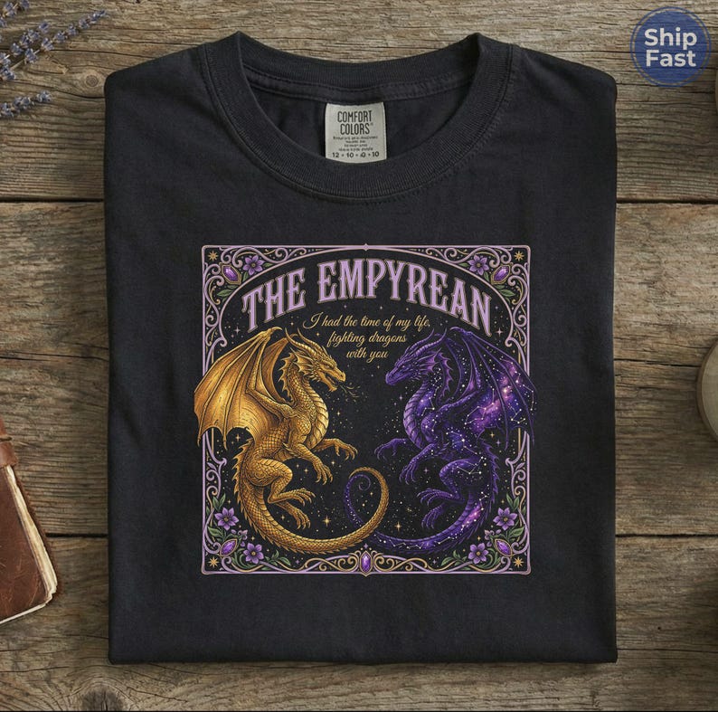 May include: Black t-shirt featuring a detailed graphic of two dragons facing each other. One dragon is gold, the other is purple with a starry wing design. The text "THE EMPYREAN" and "I had the time of my life, fighting dragons with you" are also displayed.