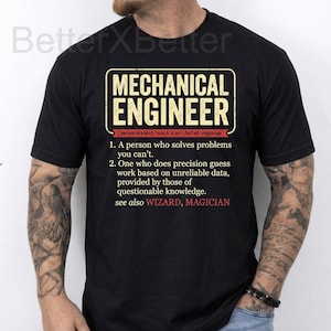 May include: Black t-shirt with the text "MECHANICAL ENGINEER" in a rectangular design. The text includes a definition of a mechanical engineer, including the phrases "A person who solves problems you can't" and "see also WIZARD, MAGICIAN."