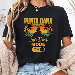 Op de afbeelding: Zwart T-shirt met een afbeelding van een zonnebril met palmbomen en de tekst "Punta Cana Vacation Mode On".
