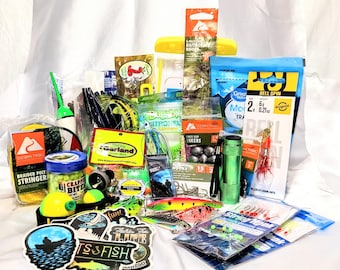 Puede incluir: Una colección de artículos de pesca, que incluye señuelos, anzuelos, pesas y sedales. Se ven varios paquetes y recipientes, con marcas como Ozark Trail y Bobby Garland. También se incluye una linterna verde y pegatinas.