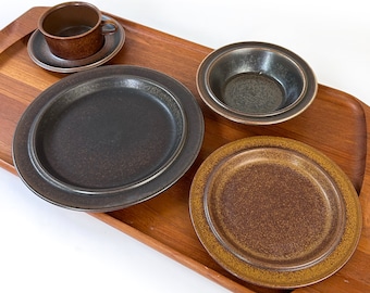 May include: A set of four brown and black ceramic plates and bowls on a wooden tray. The plates and bowls have a speckled glaze.