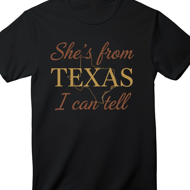 May include: Black t-shirt featuring the text "She's from TEXAS I can tell" in a brown script font. The word "TEXAS" is in a gold block font with a gold outline of the state of Texas.