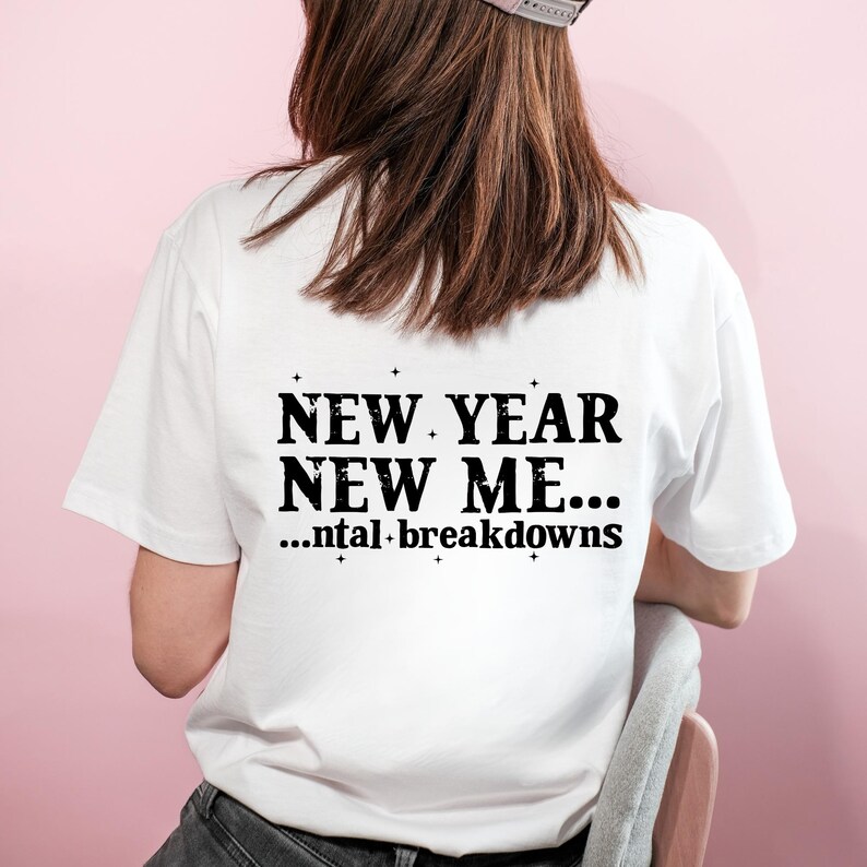 May include: White t-shirt with the text "NEW YEAR NEW ME... ...ntal breakdowns" in black. The shirt is short-sleeved and has a crew neck. The image shows the back of the shirt.