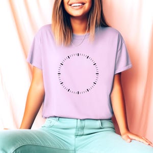 May include: A lavender t-shirt with a black clock face design on the front. The clock face has no hands.