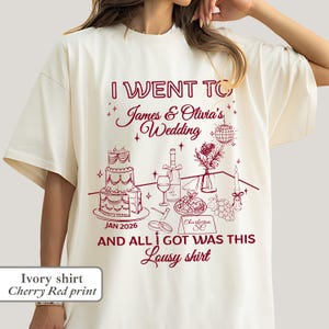 May include: Ivory-colored t-shirt with a cherry red print. The design includes the text "I Went To James & Olivia's Wedding" with wedding-themed illustrations. The text "And All I Got Was This Lousy Shirt" is also featured.
