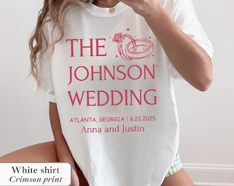 May include: White t-shirt with a crimson print. The shirt features the text "THE JOHNSON WEDDING" with a graphic of wedding rings. The text also includes the date 8.22.2025, location Atlanta, Georgia, and the names Anna and Justin.