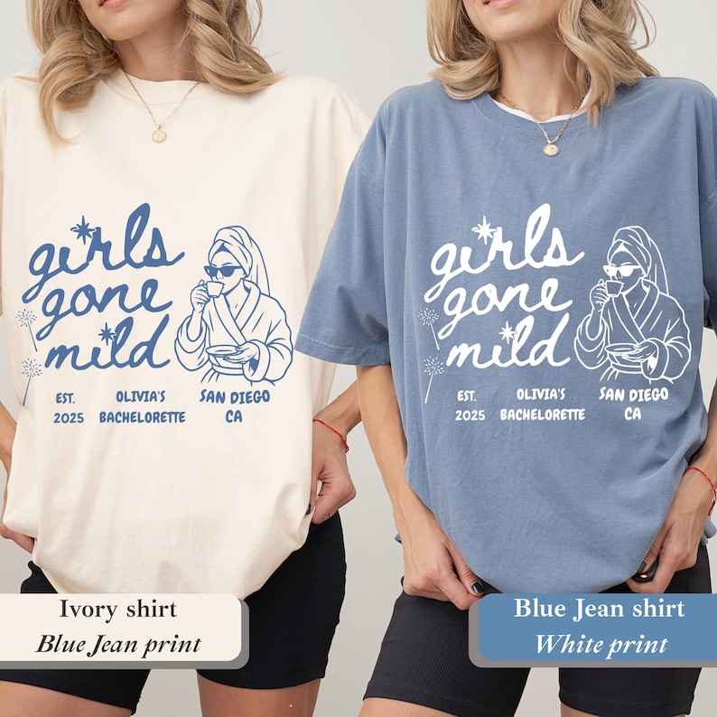 Op de afbeelding: Twee T-shirts, &eacute;&eacute;n ivoor en &eacute;&eacute;n jeansblauw, met de tekst "girls gone mild" in een scriptlettertype. De shirts hebben ook een afbeelding van een persoon in een badjas en zonnebril, die een kopje vasthoudt. De tekst "EST. 2025 OLIVIA'S BACHELORETTE SAN DIEGO CA" staat ook op de shirts.