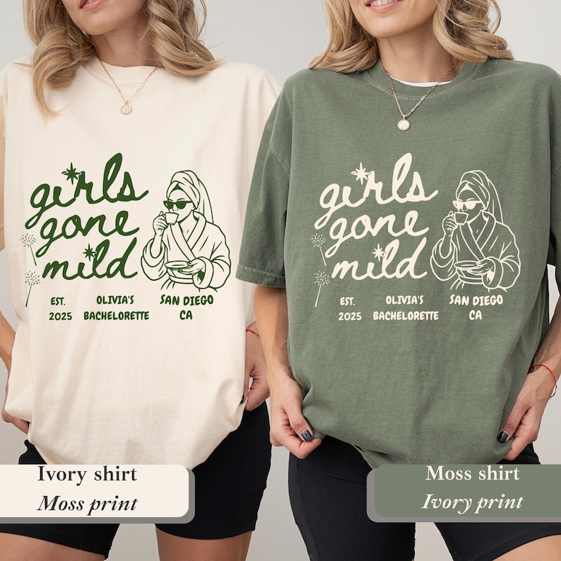 Op de afbeelding: Twee T-shirts, &eacute;&eacute;n ivoorkleurig en &eacute;&eacute;n mosgroen, tonen de tekst "girls gone mild" in een speels lettertype. Het ontwerp bevat een illustratie van een persoon in een badjas en zonnebril, die een kopje vasthoudt. Extra tekst luidt "Est. 2025 Olivia's Bachelorette San Diego CA."