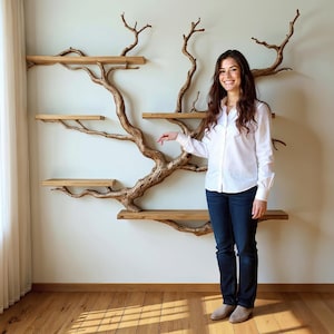 May include: A distinctive wall-mounted shelf unit crafted to mimic a tree. The shelves are constructed from light-toned wood, supported by a natural, branch-like framework. The unit is affixed to a white wall, providing a visually appealing display.