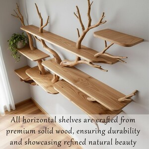 Op de afbeelding: Houten wandplanken met een natuurlijk takkenontwerp. De planken zijn gemaakt van lichtgekleurd hout en zijn aan een witte muur bevestigd. De planken hebben verschillende maten en vormen, waarvan sommige lijken te zweven. De tekst op de afbeelding luidt: Alle horizontale planken zijn gemaakt van premium massief hout, wat duurzaamheid garandeert en verfijnde natuurlijke schoonheid toont.