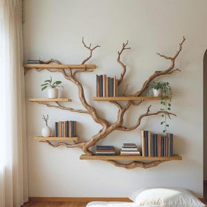 May include: A distinctive, tree-shaped bookshelf crafted from light brown wood, fixed to a white wall. The shelves are adorned with books and small potted plants, offering a natural and artistic presentation. The design embraces the wood's natural curves.
