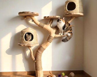 以下が含まれることがあります： ジュートロープを巻いた明るい色の天然木の枝で作られたキャットツリー。ドーム型の編み込み式猫用ベッド2つ、平らな木製プラットフォーム2つ、そしてベッドの中と枝の上にそれぞれ1匹ずつ、計2匹の猫が配置されています。