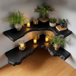 Puede incluir: Estanter&iacute;as de esquina negras con bordes naturales, plantas y velas. Las estanter&iacute;as est&aacute;n montadas en una pared gris claro y son de madera oscura. Las estanter&iacute;as tienen una forma org&aacute;nica &uacute;nica y est&aacute;n decoradas con plantas en macetas, velas y tarros de cristal.
