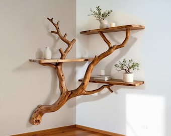 May include: A unique, handcrafted wooden corner shelf unit designed to resemble a tree. The unit features three shelves supported by natural branches, with decorative items like plants and vases displayed on the shelves. The wood has a warm, natural finish.