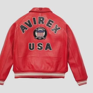 May include: A red leather jacket with the word "AVIREX" arched across the shoulders in black letters. Below the word "AVIREX" is a patch with the words "ALL AMERICANS" and "USA" in black letters. The jacket has white and red striped cuffs.